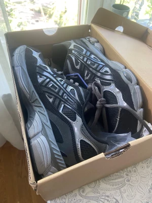 Svarta och grå sneakers från Asics stl 42 har oxå storlek 41.5, i svart men oxå stl 42 och 41.5 i babyblue färgen skriv vilken stl och färg.  - Snygga sneakers från Asics i svart och grått med meshpaneler och detaljer i silver. Skorna har en chunky sula med tydligt mönster för bra grepp och klassisk snörning. Perfekta för dig som gillar sportig stil och vill ha bekväma skor till vardags.