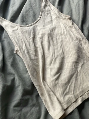 Vit ribbad linnetopp från h&m - Säljer en enkel och stilren vit ribbad linnetopp från h&m. Toppen är ärmlös med rund halsringning och har en mjuk, stretchig känsla som passar perfekt till alla tillfällen. Superskön och lätt att matcha med olika outfits.