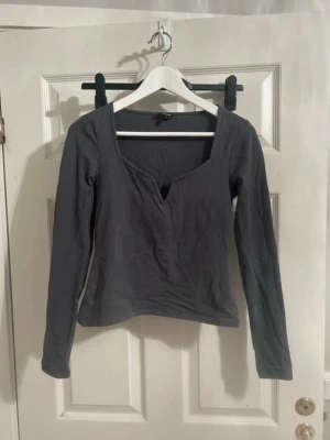 Grågrön långärmad topp Bubbleroom - Gröngrå långärmad topp från Bubbleroom med unik v-ringad halsringning. Tillverkad i mjukt material som känns skönt mot huden. Perfekt att styla med jeans eller kjol för en trendig look.