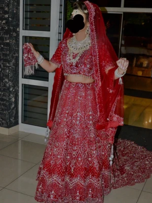 Röd bridal lehenga - Säljer en fantastisk röd lehenga med detaljerad brodyr och gnistrande paljetter. Klänningen har matchande slöja och crop top med korta ärmar. Perfekt för speciella tillfällen och ger en riktigt elegant look.