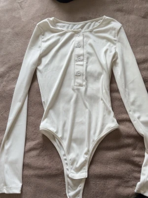 Vit ribbad långärmad body - Snygg enkel vit body med långa ärmar. Aldrig använd!