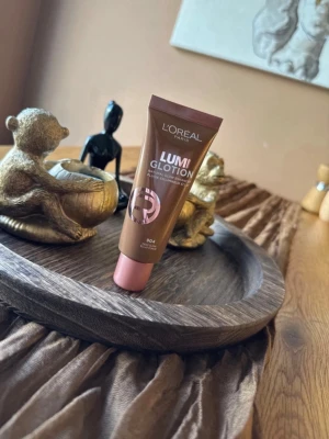 L'Oréal Lumi Glotion 904 Deep Glow - L'Oréal Lumi Glotion i nyansen 904 Deep Glow ger huden en naturlig lyster och glow. Tuben är brun med rosa lock och innehåller en flytande foundation som smälter in i huden. Perfekt för dig som vill ha en fräsch och återfuktad look.