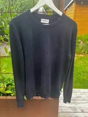 Mörkgrå stickad tröja Lindbergh - Mörkgrå stickad tröja från Lindbergh med rund halsringning och ribbade muddar vid ärmslut och nederkant. Tröjan har en enkel och stilren design, perfekt för lager på lager och passar till det mesta. Materialet ser mjukt och bekvämt ut.