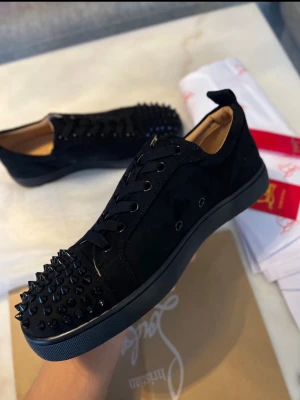 Christian Louboutin sneakers med nitar - Säljer ett par svarta sneakers från Christian Louboutin med coola svarta nitar