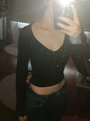 croppad topp Gina Tricot - svart croppad topp från Gina Tricot med v-ringad hals. Toppen är ribbad och sitter tight, jätte snygg till lågmidjade jeans. Använd några få gånger.