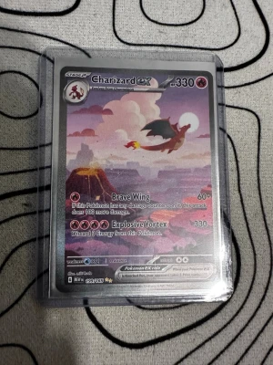 Charizard EX Pokémonkort - Säljer ett Charizard EX Pokémonkort. Kortet har en färgstark illustration med Charizard som flyger över ett landskap i rosa och lila toner. Kortet ligger i ett plastfodral för extra skydd 