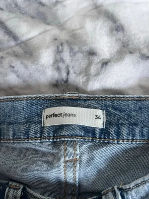Ljusblå bootcut jeans från Perfect Jeans - Säljer ett par ljusblå bootcut jeans från Perfect Jeans (gina tricot) i storlek 34. Jeansen har klassisk femficksdesign och utsvängda ben. Tillverkade i ett mjukt denimtyg som ger en skön passform och trendig look.