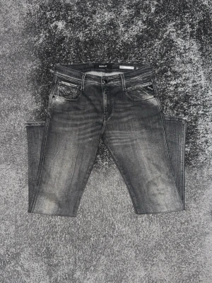 Grå tvättade jeans från Replay - Snygga grå jeans från Replay med tvättad look och klassisk femficksmodell. Jeansen har raka ben, normal midja och detaljerade sömmar på bakfickorna. Perfekta för en avslappnad och trendig stil.