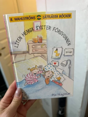 Liten hemsk syster försvunnen - En lättläst kapitelbok från B. Wahlströms om Julia och hennes lillasyster Isabell. Omslaget är färgglatt med illustration av två barn i ett sovrum. Boken har hårda rosa pärmar och är skriven av Pia Hagmar. Perfekt för unga läsare som gillar vardagsdrama.
