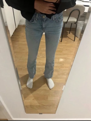 Ljusblå flared jeans med mid midja - Säljer ett par ljusblå jeans med flared passform och mid midja. Jeansen har klassisk femficksdesign och stängs med knapp och dragkedja. Perfekta till en avslappnad stil och passar till det mesta i garderoben.