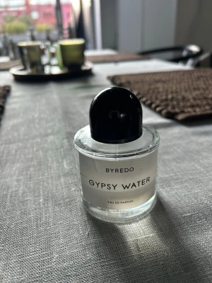 Byredo Gypsy Water Eau de Parfum - Byredo Gypsy Water Eau de Parfum i en stilren, rund glasflaska med svart lock. Doften är ikonisk och flaskan har en minimalistisk vit etikett med svart text. Perfekt för dig som gillar exklusiva och unika parfymer.  Ungefär 50% kvar.