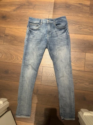 Blå slim fit jeans från Balmain - Säljer ett par snygga blå skinny jeans från Balmain Paris. Jeansen har en klassisk femficksmodell, slitna detaljer och ljus tvätt. Perfekta för dig som gillar en trendig och avslappnad stil.