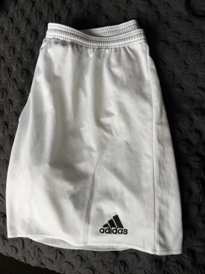 Vita shorts från Adidas - Säljer ett par klassiska vita shorts från Adidas i storlek XL. Perfekta för sport.