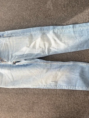Ljusblå jeans från Tiger of Sweden - Säljer ett par ljusblå jeans från Tiger of Sweden med klassisk femficksmodell och dragkedjegylf. Jeansen har raka ben och är tillverkade i mjukt denimtyg. Perfekta för en avslappnad och stilren look.