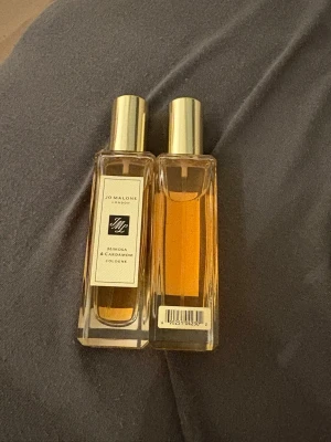 Jo Malone Mimosa & Cardamom Cologne - Jo Malone Mimosa & Cardamom Cologne i elegant, rektangulär glasflaska med guldfärgad kork. Doften har en varm, kryddig och blommig karaktär med inslag av mimosa och kardemumma. Flaskan har en stilren etikett och innehållet är bärnstensfärgat. Du får en för 600 kr och båda för 1200 kr