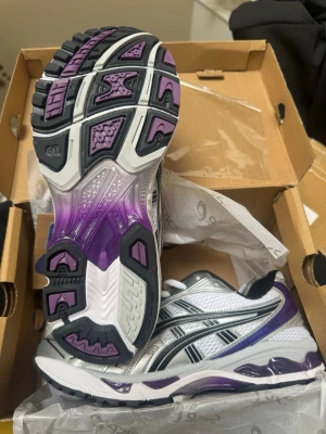 Vita och lila sneakers från Asics - Snygga sneakers från Asics i vitt, silver och lila med svarta detaljer. 