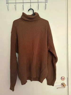 Brun polotröja från Brandy Melville - Stickad brun polotröja från Brandy Melville med oversized passform och grov ribbstickning. Onesize men skulle uppskatta den som en stor M eller L. Tröjan har långa ärmar och hög krage som går att vika ner. Köpte på Brandy Melville i Stockholm för ett par år sedan men aldrig använt, då jag inte bor där kunde jag inte retunera så har bara legat i garderoben ett par år nu.