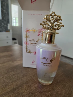 Nuha Vanilla Pearl - Nuha Vanilla Pearl Eau de Parfum från Khadlaj i en elegant pärlemorskimrande glasflaska med exklusiv guldfärgad dekorativ kork. Doften har en söt  bärig och mjuk vaniljkaraktär. Flaskan levereras i en vit och guldrosa kartong med blommiga detaljer. Innehåll se bilder.