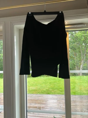 Svart långärmad tröja med v-ringning - En stilren svart långärmad tröja med djup v-ringning. Tröjan har en smickrande passform och är perfekt att matcha med både jeans och kjol. Enkel design utan mönster och med långa ärmar.