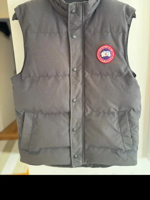 Canada goose väst  - Svart dunväst från Canada Goose i stl M, normal i storleken. Dragkedja med tryckknappar fram, två fickor och klassisk rund logga på bröstet. Västen är i mycket sparsamt sick.