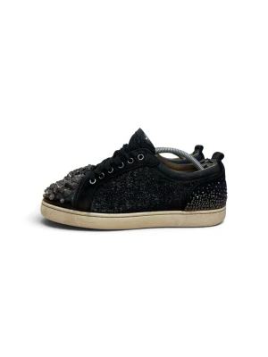 Svarta sneakers med nitar och glitter - Unika svarta sneakers med glittrande tyg, dekorerade med silverfärgade nitar på tån och hälen. Skon har en vit sula och klassisk röd undersida. Snygg och edgy design som sticker ut i mängden.