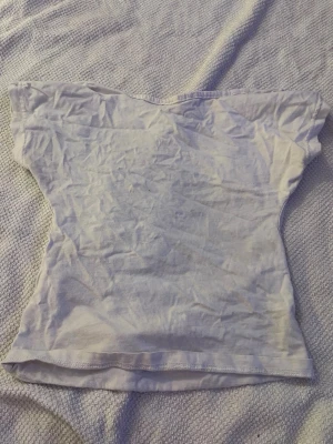 Vit topp med öppen rygg - En enkel vit topp med öppen rygg. Passar perfekt till jeans eller kjol för en clean och fräsch look. Tyget är tunt och lätt, vilket gör den skön att bära under varma dagar.