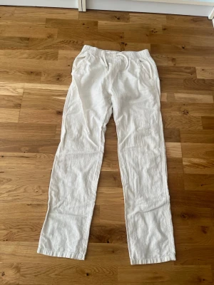 Vita linnebyxor från Lindex - Säljer ett par vita linnebyxor från Lindex med avslappnad passform och resår i midjan med dragsko. Byxorna har raka ben och sidofickor. Perfekta för en chill och stilren look under varma dagar.
