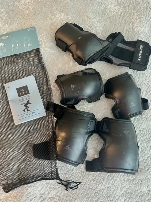 Svart skyddsutrustning från Firefly L - Säljer ett set svart skyddsutrustning från Firefly, modell FWP 2.0. Setet innehåller knäskydd, armbågsskydd och handledsskydd, perfekt för skateboard eller inlines. Kommer med praktisk förvaringspåse. Snygg och sportig design i svart plast och mesh.