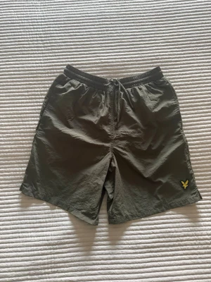 Olivgröna badshorts  Lyle & Scott - Säljer ett par olivgröna badshorts med elastisk midja och snörning framtill.