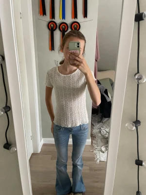 Vit virkad topp med kort ärm - Säljer en söt vit virkad topp med korta ärmar och rund hals. Toppen har ett luftigt, genombrutet mönster och sitter figurnära. Perfekt att styla med jeans eller kjol för en trendig look.