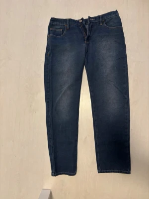 Mörkblå raka jeans - Snygga mörkblå jeans med raka ben och klassisk femficksdesign. Jeansen har normal midja, dragkedja och knapp framtill samt kontrastsömmar. Tillverkade i denim med lätt tvättade detaljer för en avslappnad look.