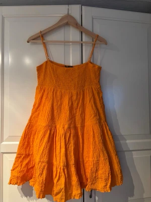 Gul sommarklänning från Zara - Säljer en solgul kort klänning från Zara med smala axelband och rynkad överdel. Klänningen har en luftig, volangig kjol och är tillverkad i ett lätt bomullstyg – perfekt för varma dagar.