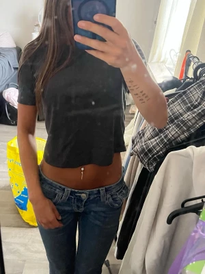 Grå croppad t-shirt från Zara - Säljer en grå croppad t-shirt från Zara i ribbad bomull. T-shirten har korta ärmar och en tight passform som framhäver midjan. Perfekt till jeans eller kjol för en enkel och snygg look.