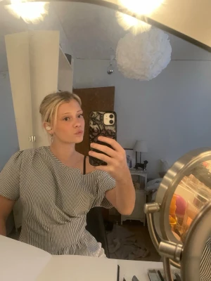 Randig oneshoulder topp - Säljer en snygg randig topp med oneshoulder-design. Toppen har smala svarta och vita ränder och är kortärmad på ena sidan medan andra axeln är bar. Perfekt för dig som vill sticka ut lite extra!