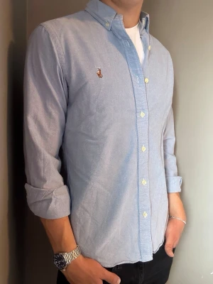 Ralph Lauren skjorta ljusblå – M slim fit - Säljer denna stilrena och snygga ljusblåa Ralph Lauren skjortan. Skjortan är i mycket bra skick och storlek M slim fit. Perfekt för både vardag och mer uppklädda tillfällen. Har du några frågor? Tveka inte att höra av dig. Allt gott från Deluxe Garderoben ⭐️ 