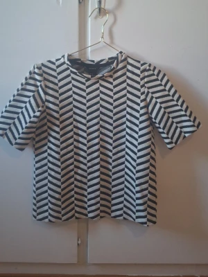 Randig topp från Lindex XS - Snygg kortärmad topp från Lindex i storlek XS. Toppen har ett svartvitt, randigt mönster i sicksack och en rund halsringning. Perfekt att styla med jeans eller kjol för en trendig look.