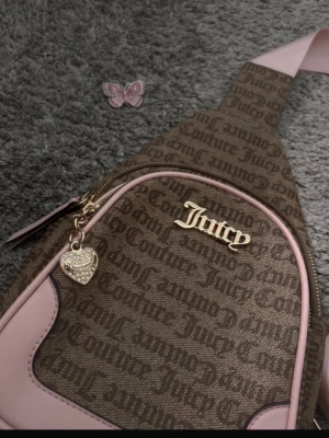 Juicy Couture väska 💕✨ - Köparen står för frakt. Säljer en fin väska från Juicy Couture som kan användas både som sidoväska och ryggsäck. Axelremmen är justerbar och kan enkelt flyttas så att du kan bära väskan på både höger eller vänster sida – praktisk och snygg på samma gång.  ✨ Märke: Juicy Couture✨ Skick: Bra skick.✨ Kan användas både som sidoväska och ryggsäck.✨ Justerbar rem som kan bytas mellan höger och vänster sida.✨ Perfekt till både vardag och resa.  Hör gärna av dig om du har frågor eller vill ha fler bilde