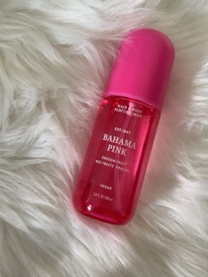 Bahama Pink - Fräsch parfymmist för hår och kropp i doften Bahama Pink med noter av drakfrukt, röda bär och pralin. Flaskan är cylinderformad i genomskinlig rosa plast med matchande rosa lock. Vegansk formula och smidig storlek på 100 ml.