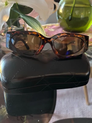 Bruna cat eye solglasögon - Säljer ett par trendiga solglasögon i cat eye-modell med brunmelerad båge och bruna glas. Snygg retrostil som ger en cool vibe till din outfit. Kommer med ett svart quiltat fodral.