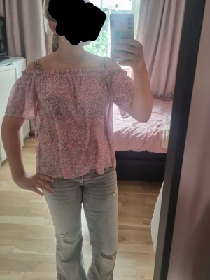 Rosa off shoulder blommig topp - Söt off shoulder topp i rosa med småblommigt mönster och korta ärmar. Toppen har resår vid axlarna och knytband på axlarna för extra detalj, men funkar utan dem också! Den är väldigt tunn så den kan bli lite genomskinlig, men inget som stör. Har prislapp på, nypris 199 från hm. Strl 38. Kom gärna med prisförslag. 