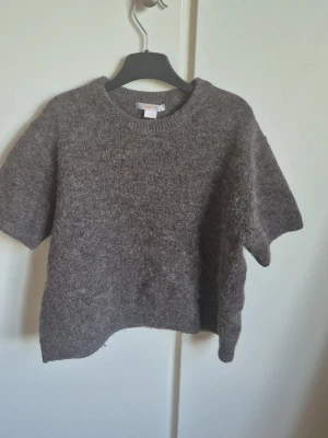 Grå stickad t-shirt - Mysig grå stickad t-shirt med korta ärmar och rund hals. Tror tröjan har krympt lite i tvätten men inte mycket. 