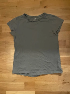 Mörk grön basic t-shirt från H&M - En enkel mörk grön t-shirt från H&M Basic i ekologisk bomull. T-shirten har rund halsringning och korta ärmar. Perfekt till vardags och lätt att matcha med olika stilar.