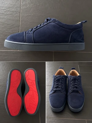 Mörkblå louboutin mocka sneakers - Snygga mörkblå sneakers i mocka med klassisk låg profil och matchande blå snörning. Skorna är synligt använda på undersidan av skon som har blivit bort redgerat och inuti. Skorna har en unik röd sula med mönster och en diskret design som passar till många stilar. Insidan är ljusbeige och sulan är i gummi.