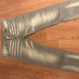 Grå Dsquared2 jeans  - Säljer ett par grå jeans från Dsquared2 med coola blekta effekter och klassisk femficksdesign. Byxorna har raka ben och snygg Dsquared2-patch bak. Materialet är bomull och passformen är slim, perfekt för dig som gillar streetstyle.