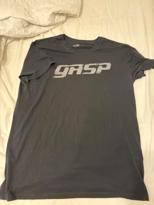 Svart GASP t-shirt med tryck - Säljer en svart t-shirt från GASP i storlek M passar också till L. T-shirten har ett stort, slitet GASP-tryc på bröstet och kl. passar perfekt till en avslappnad stil. 