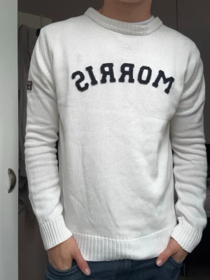 Vit stickad Morris tröja  - Vit stickad tröja från Morris med svart broderad Morris logga på bröstet. As fet som layerplagg under overshirt och passar till allt! Lätt ett av mina favoritplagg!!!