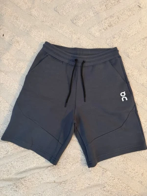 On cloud shorts - Snygga mörkgrå shorts från On cloud med  två sidofickor och en extra innerficka med dip. Skönt material som kan användas för träning men också att chilla i. Kom privat vid funderingar.