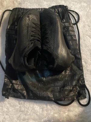 Vapor 16 Elite FG - Ett par ZM Vapor 16 Elite Fg Nike fotbollsskor i black-deep jungle färg. Sköna och snygga fotbollsskor i storlek 42,5 som sitter väldigt bra när man spelar fotboll. Tillkommer även gympapåse och kartong!