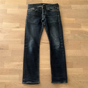Mörkblå Replay jeans straight fit - Snygga mörkblå jeans från Replay med diskreta slitningar. Jeansen har raka ben och slim passform, med detaljerade sömmar och logga på bakfickan. Storleken är 28/32 men skulle snarare säga att de passar 27/30. Byxorna är bra för dig som är runt 165cm. 