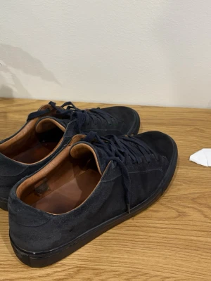 Mörblåa sneakers från skolyx - Snygga mörkblå sneakers i mocka med klassisk låg profil och matchande mörkblå snören. Insidan är fodrad i brunt läderliknande material. Skorna har använts i 2 månader och är i mycket bra skick. Nypris 1600 och jag säljer för 550 kr